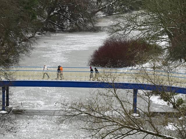 Walkers crossing Ha'penny Bridge over a frozen River Kelvin in Glasgow on Friday. Picture: John Devlin