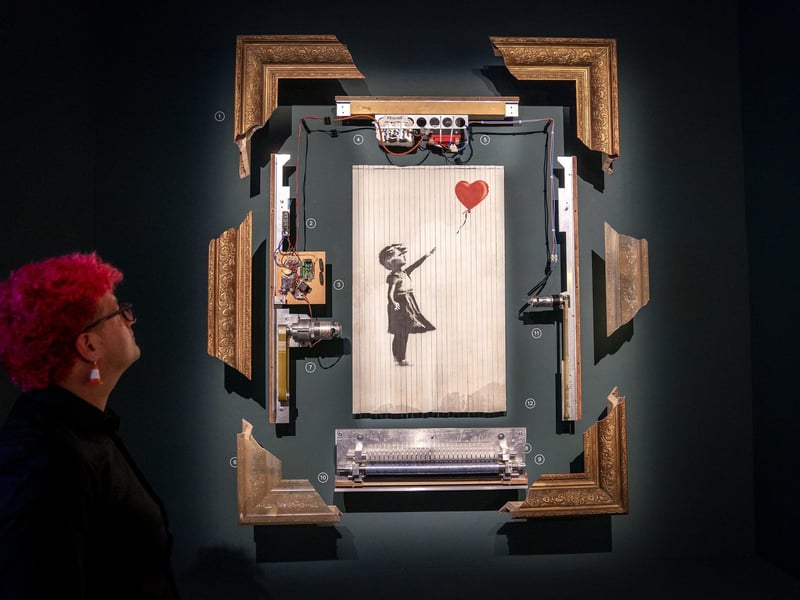 Gallery steward Louisa Mcgeachie takes a closer look at Going Going Gone, the stencil piece of the girl with the heart balloon that was shredded live during an auction at the new show by artist Banksy 'Cut & Run' opens this Sunday at Glasgow's GoMA.