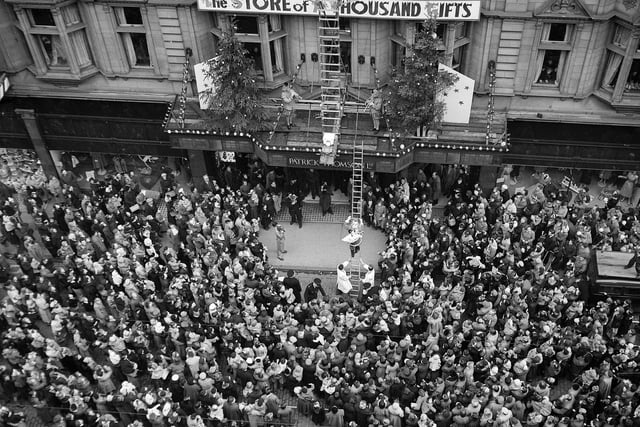 Crowds outside Patrick Thomson's department store in Edinburgh as  Santa Claus climbs down a golden ladder in November 1955.