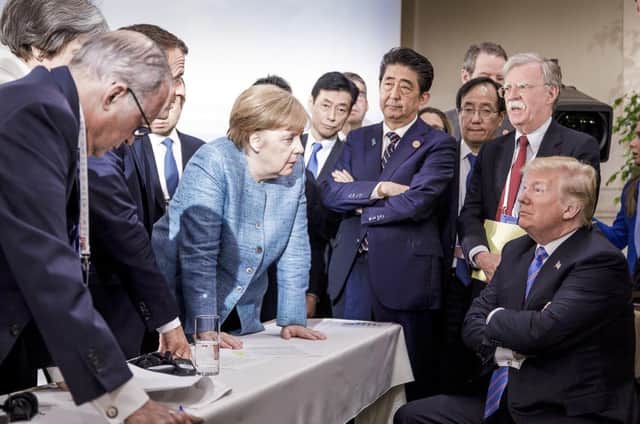 In one of the least diplomatic photos ever,  German Chancellor Angela Merkel speaks with U.S. President Donald Trump, seated at right, during the G7 Leaders Summit in La Malbaie, Quebec, Canada, on Saturday, June 9, 2018.  Trump left the summit early and refused to endorse the official statement - calling Canadian Prime Minister Justin Trudeau "very dishonest and weak"