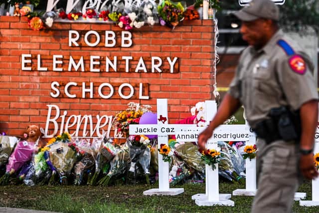 A police officer walks past a makeshift memorial for the shooting victims at Robb Elementary School in Uvalde, Texas on June 7, 2022, after an 18-year-old gunman slaughtered 19 children and two teachers
