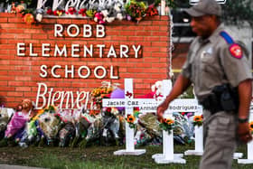 Police officers walk past a makeshift memorial for the shooting victims at Robb Elementary School in Uvalde, Texas. - US authorities warned on June 7, 2022, of possible copycat mass shootings after an 18-year-old gunman slaughtered 19 children and two teachers at Robb Elementary School in Texas, two weeks ago. (Photo by CHANDAN KHANNA / AFP) (Photo by CHANDAN KHANNA/AFP via Getty Images)