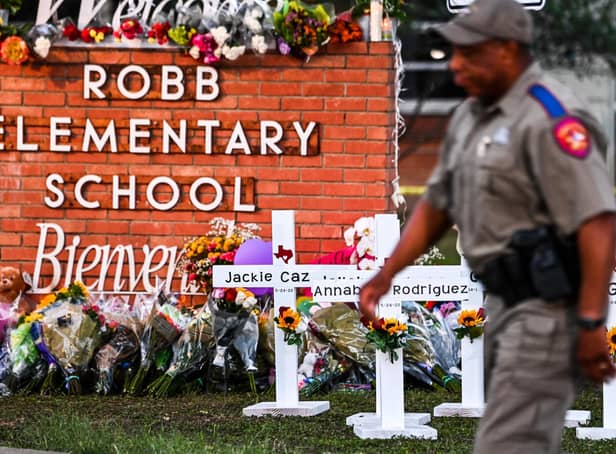 Police officers walk past a makeshift memorial for the shooting victims at Robb Elementary School in Uvalde, Texas. - US authorities warned on June 7, 2022, of possible copycat mass shootings after an 18-year-old gunman slaughtered 19 children and two teachers at Robb Elementary School in Texas, two weeks ago. (Photo by CHANDAN KHANNA / AFP) (Photo by CHANDAN KHANNA/AFP via Getty Images)