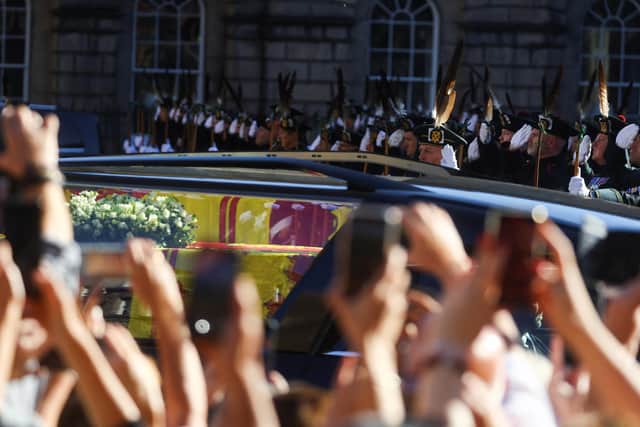 Members of the Royal Archers salute as a hearse carries the coffin of Elizabeth II from St Giles Cathedral