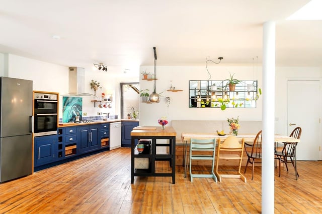 The kitchen itself is discreetly zoned to maximise the useable floorspace. It is fitted with base cabinets and topped with an L-shaped worksurface, appointed in dark blue and wooden tones (respectively). It is an attractive design that adds to the style of the open-plan room. In addition, it comes with a range of integrated and freestanding appliances. A neighbouring utility room supplements the kitchen with a discreet space for laundry.