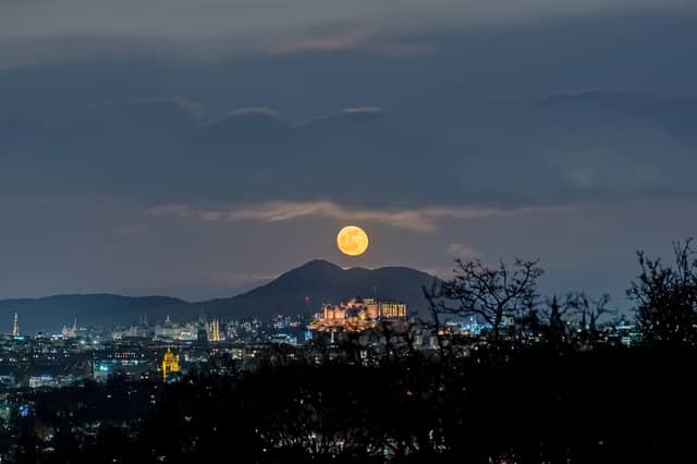 This spectacular image shows a ghostly, spectre-like moon hanging above Edinburgh Castle
