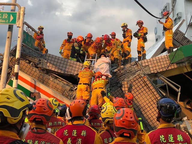 This handout photo taken and released  by the Taitung County Fire Bureau shows firefighters moving a person during a rescue operation at the site of a collapsed building (via Getty Images)