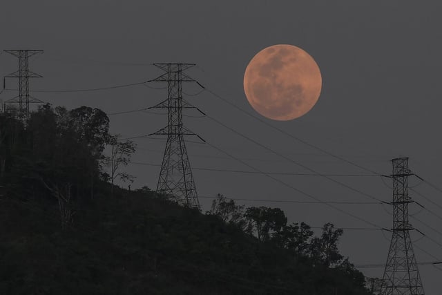 A full moon rises behind the high voltage towers of the El Avila in Caracas, Venezuela, Sunday, May 15, 2022 (AP Photo/Matias Delacroix)