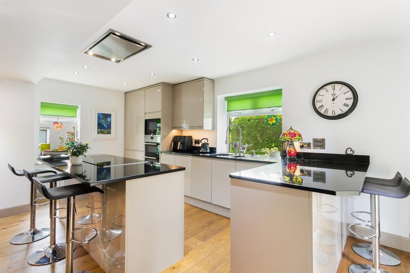 The kitchen is beautifully appointed with contemporary off-white cabinets, spacious and gleaming stone worktops, providing ample storage and workspace. The room is filled with natural light through tripleaspect windows, whilst a door affords access to the rear garden.