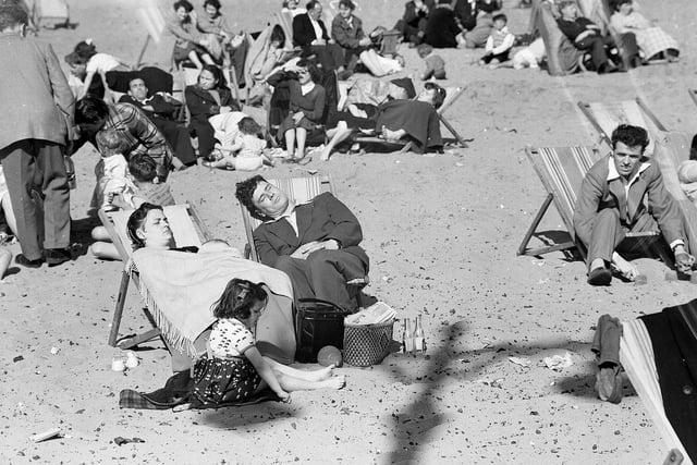 A mother and father sleeping in deck chairs on Portobello Beach in 1955.
