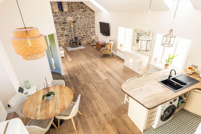 The bright and spacious open-plan lounge/kitchen/diner with a log burner, triple-aspect outlook, beautifully exposed original brickwork, floor spotlights and Velux windows.