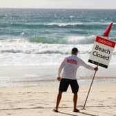 A Gold Coast Lifeguard erects a Beach Closed sign at Surfers Paradise in April 2020 (Photo: Chris Hyde/Getty Images)