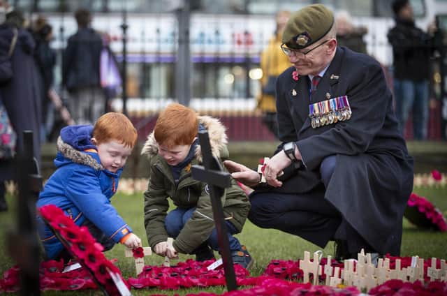 Former Scots Guard Brian Ward, from Cumbernauld, with his two sons Daniel, two (left) and Jack, four, place crosses in the Edinburgh Garden of Remembrance on 11 November last year (Picture: Jane Barlow/PA Wire)