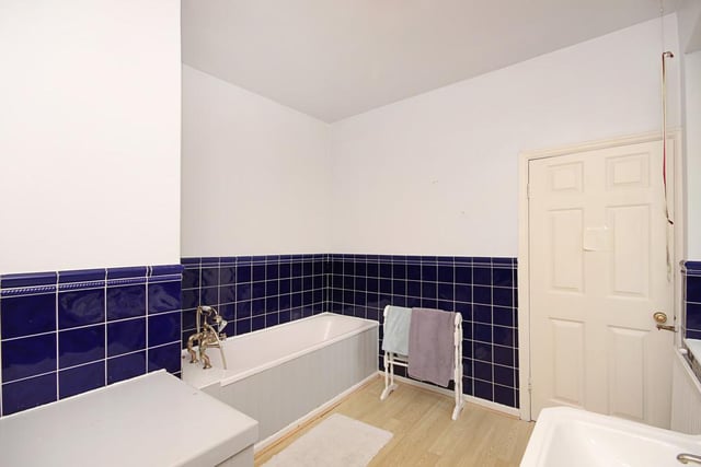The bathroom contains a panelled bathtub and is tiled in a deep shade of blue.