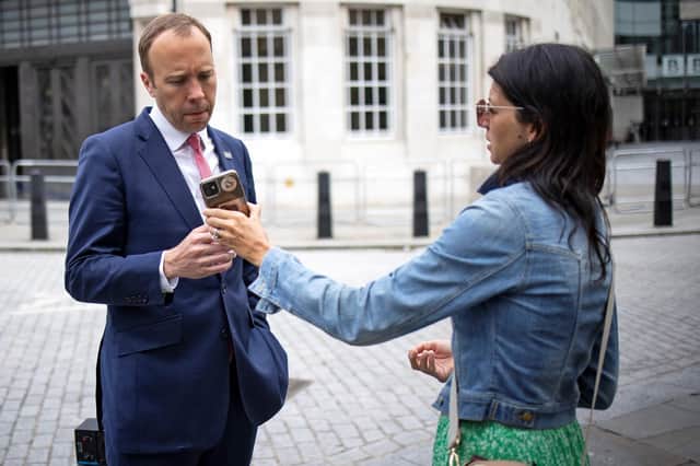 Matt Hancock looks at the phone of his aide Gina Coladangelo last month, two weeks before it emerged they were having an affair (Picture: Tolga Akmen/AFP via Getty Images)