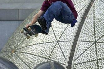 Utilising the unique concrete ball designs in front of the Sheraton Hotel on Lothian Road, one skateboarder goes flying. 16 October 2001