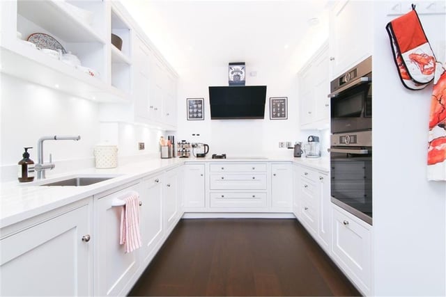 Kitchen with chic white cabinets, acrylic worktops, accent lighting, combi electric/gas hob, electric double oven, fully integrated dishwasher and washing machine.