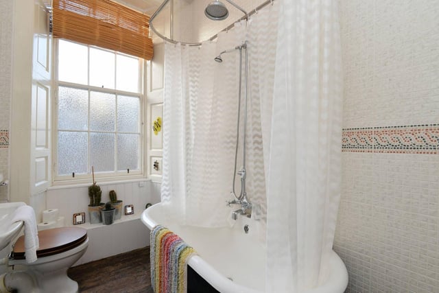 The bathroom completes the accommodation. Tiled and boasting a vintage feel, the bathroom has a roll-top bath with an overhead mains shower, a white suite with traditional fixtures, exposed floorboards, and ample natural light