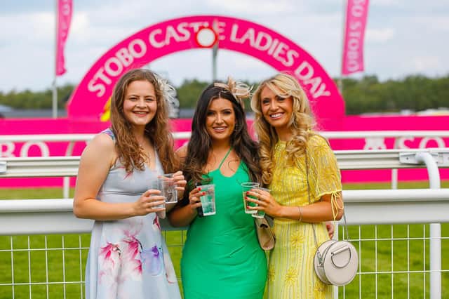Three stylish racegoers stop for a photo as they wait for the races to begin.