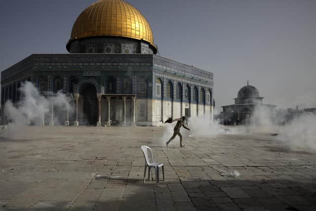A Palestinian man runs away from tear gas during clashes with Israeli security forces in front of the Dome of the Rock Mosque in Jerusalem (Picture: Mahmoud Illean/AP)