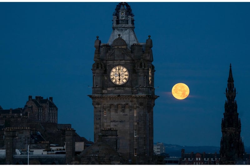 The blue supermoon sets between the Balmoral Clock and the Scott Monument in Edinburgh.