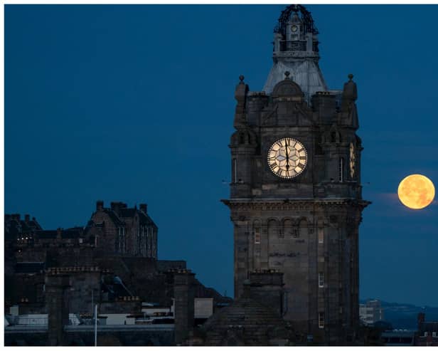 The blue supermoon sets between the Balmoral Clock and the Scott Monument in Edinburgh.