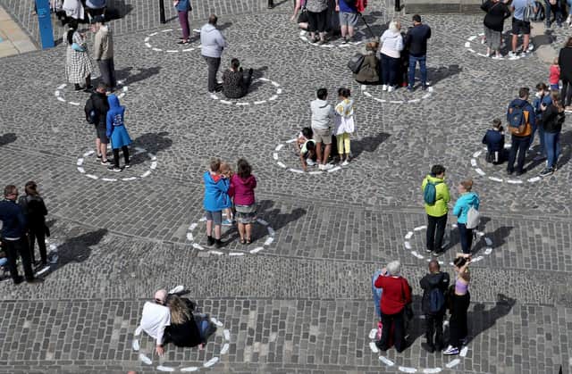 Visitors at Edinburgh Castle stand socially distanced in marked out circles as they watch the daily one o'clock gun ceremony.