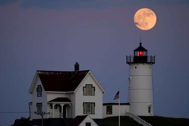 A waxing gibbous moon is seen at 98% percent full as it rises near the Nubble Light, Monday, June 13, 2022, in York, Maine.