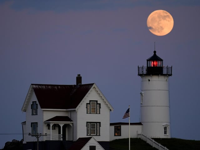 A waxing gibbous moon is seen at 98% percent full as it rises near the Nubble Light, Monday, June 13, 2022, in York, Maine.