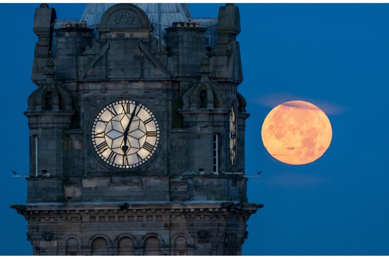 The blue supermoon sets behind the Balmoral Clock in Edinburgh.