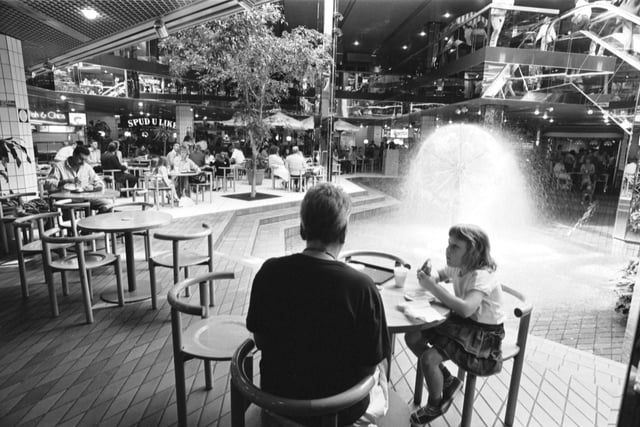 People eating in the Food Court at Waverley Market shopping centre in Edinburgh, with the fountain in the centre, July 1988.