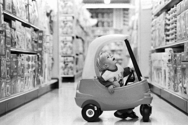 Two-year-old Kieran Casey in his pedal car, amazed at all the toys on sale in the Toys R Us superstore in Edinburgh, September 1989.