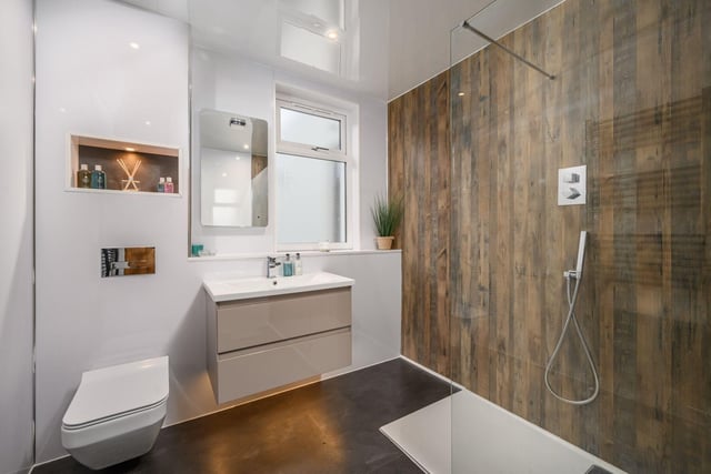 The modern fully panelled shower room with a walk-in rainfall shower, underfloor heating and heated towel rail.