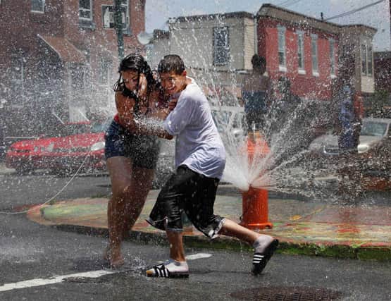 Children play under a fire hydrant spraying water in a hot  New York