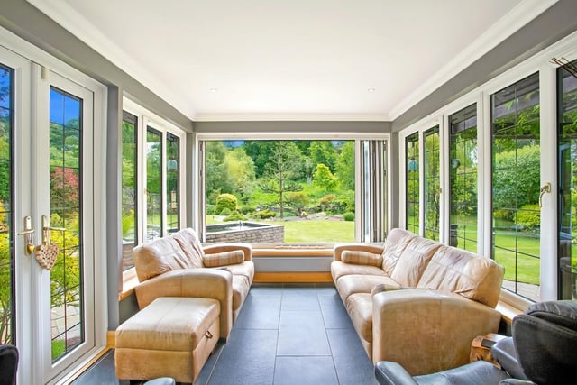 The garden room is filled with natural light through triple-aspect glazing (including bi-folding windows) framing views of the garden, with French doors affording direct access outside.