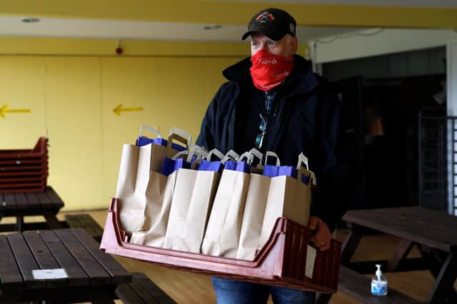 A volunteer loads bags of meals into a car