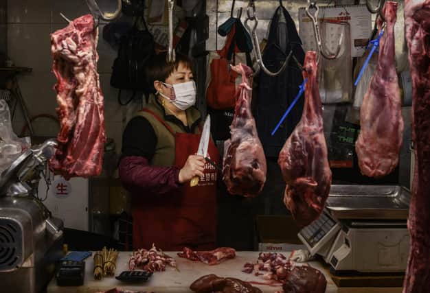 A butcher wears a protective mask as she works in her stall at a local market in China's capital Beijing (Picture: Kevin Frayer/Getty Images)