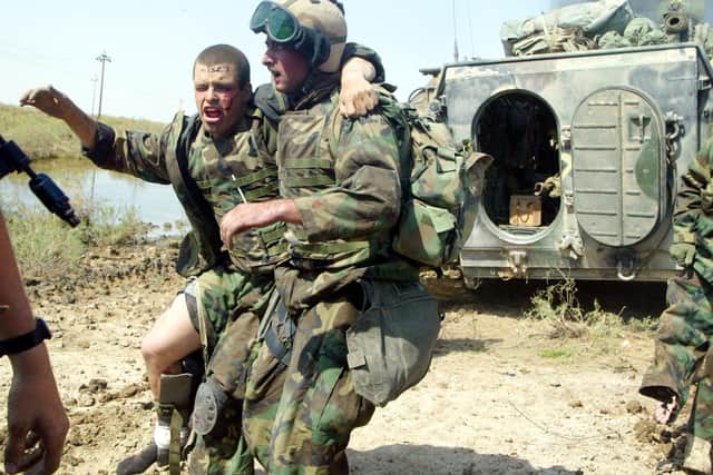 US Marines help a wounded man while being pinned down by enemy fire in the southern Iraqi city of Nasiriyah in March 2003 (Picture: Joe Raedle/Getty Images)