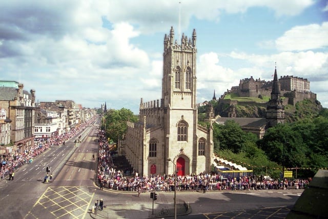 The junction of Lothian Road and the west end of Princes Street in September 1992, with the sandstone St John's Episcopal Church and the darker spire of St Cuthbert's Church of Scotland to its right, in front of Edinburgh Castle.