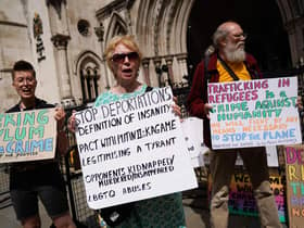 Demonstrators hold placards as they protest against the Rwanda asylum plan outside the High Court in London yesterday