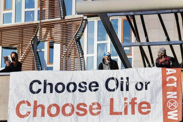 On October 8, activists from XR climbed onto the roof of the Scottish Parliament and unveiled a Trainspotting-style banner that read “Choose Oil or Choose Life”. (Photo by Jeff J Mitchell/Getty Images)