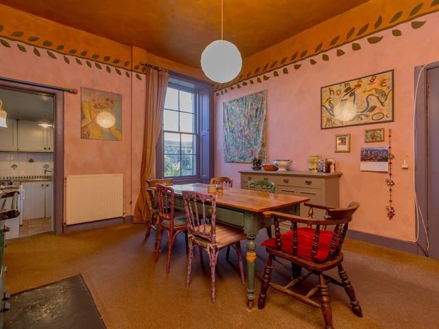 The dining room has a Rayburn and a window to the rear, with a doorway leading through to the kitchen.