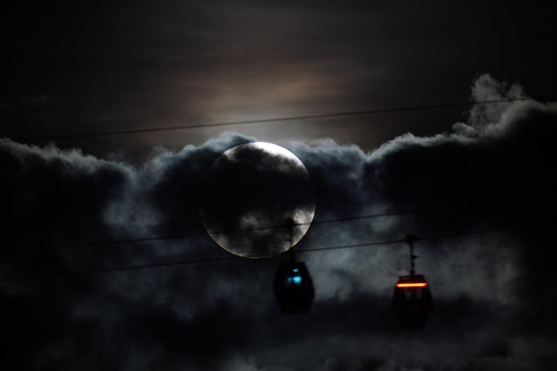 The super blue moon hidden behind clouds as IFS Cloud Cable Cars pass by at Greenwich.