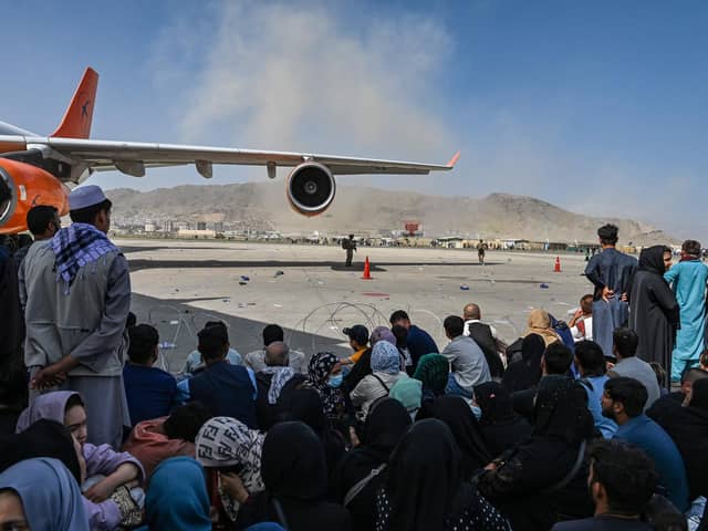 People sit on the tarmac as they wait to leave the Kabul airport on Monday following the Taliban's takeover of the city (Picture: Wakil Kohsar/AFP via Getty Images)