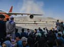 People sit on the tarmac as they wait to leave the Kabul airport on Monday following the Taliban's takeover of the city (Picture: Wakil Kohsar/AFP via Getty Images)