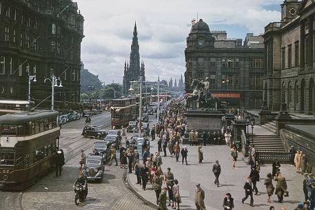 View of trams, cars and pedestrians making their way along Princes Street during Edinburgh Festival in August 1947. The General Register House is visible on right with the Balmoral Hotel and clocktower on left.