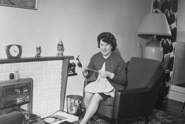 Mrs Mary Eves relaxing in her sitting room at her new home, knitting by the fireplace. April 1966