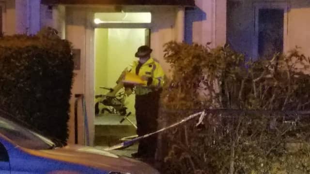 A police officer stands outside the doorway to the block of flats in Muirhouse Place West.