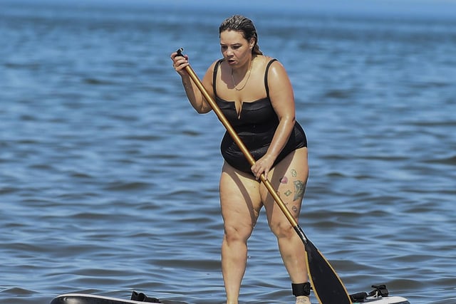 A woman takes to the sea on a paddle board as she enjoys the sun.