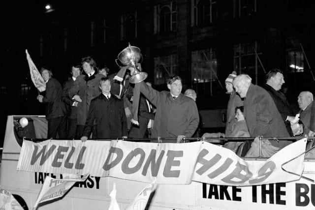 Hibs manager Eddie Turnbull lifts the cup, flanked by his players on his right, and Hibs directors including former Easter Road goalkeeper Tommy Younger and chairman Tom Hart, on the left